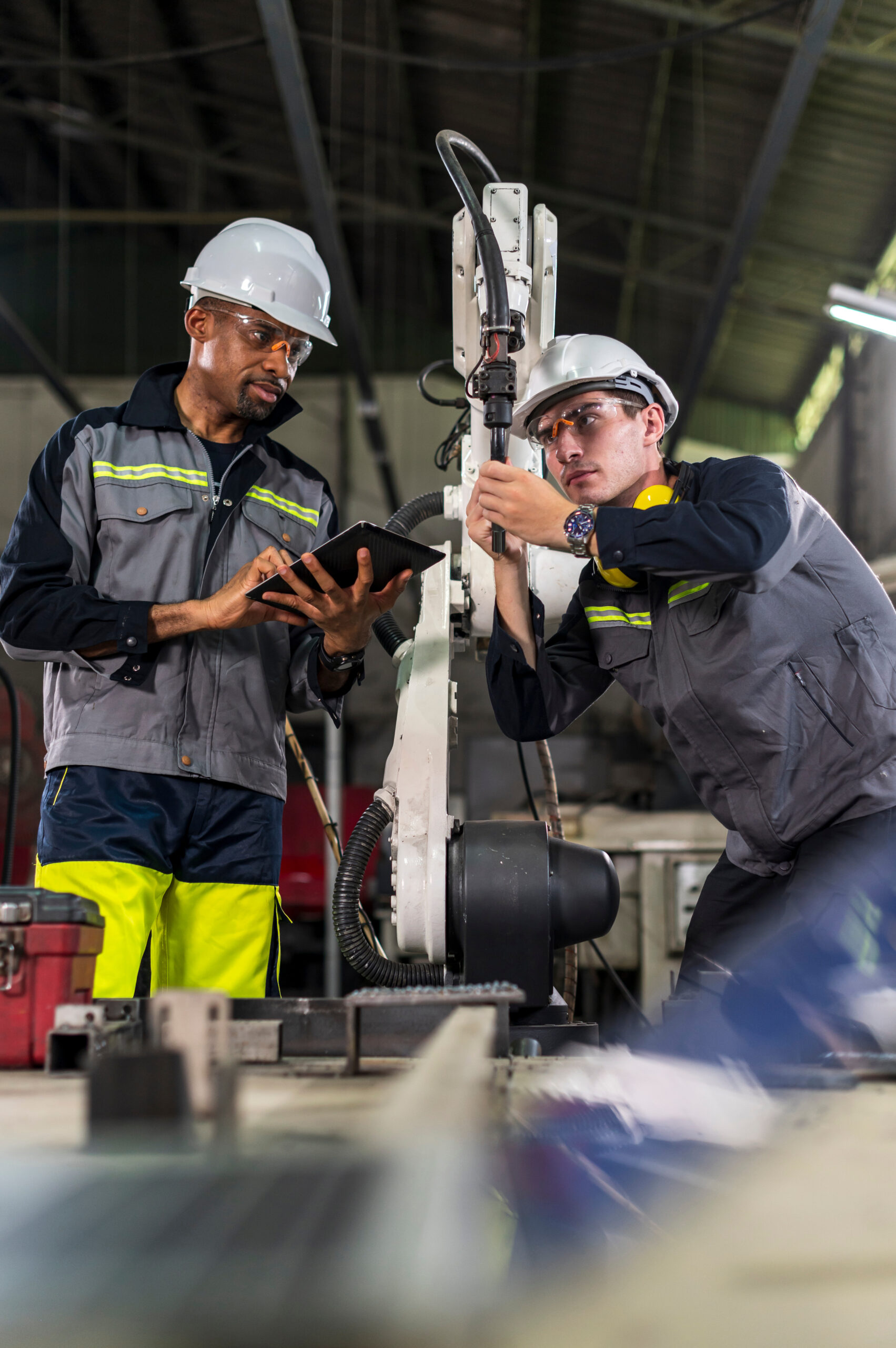 Robotics control engineers setting and maintain spare parts of industrial robot arm controller in production plant factory