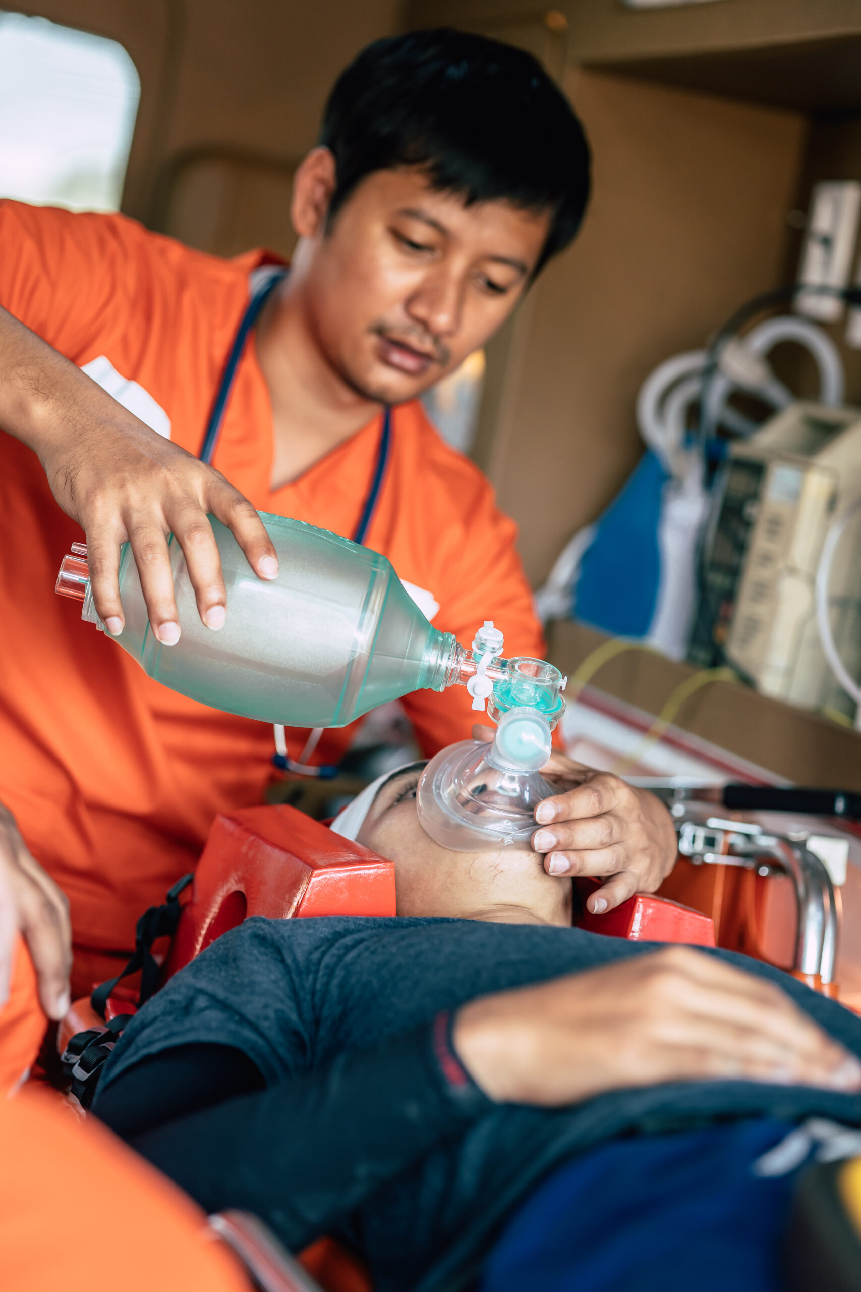 Paramedics Emergency EMS team using Reusable Manual Resuscitator or Ambu Bag to help accident patient breathing in hospital car mobile unit