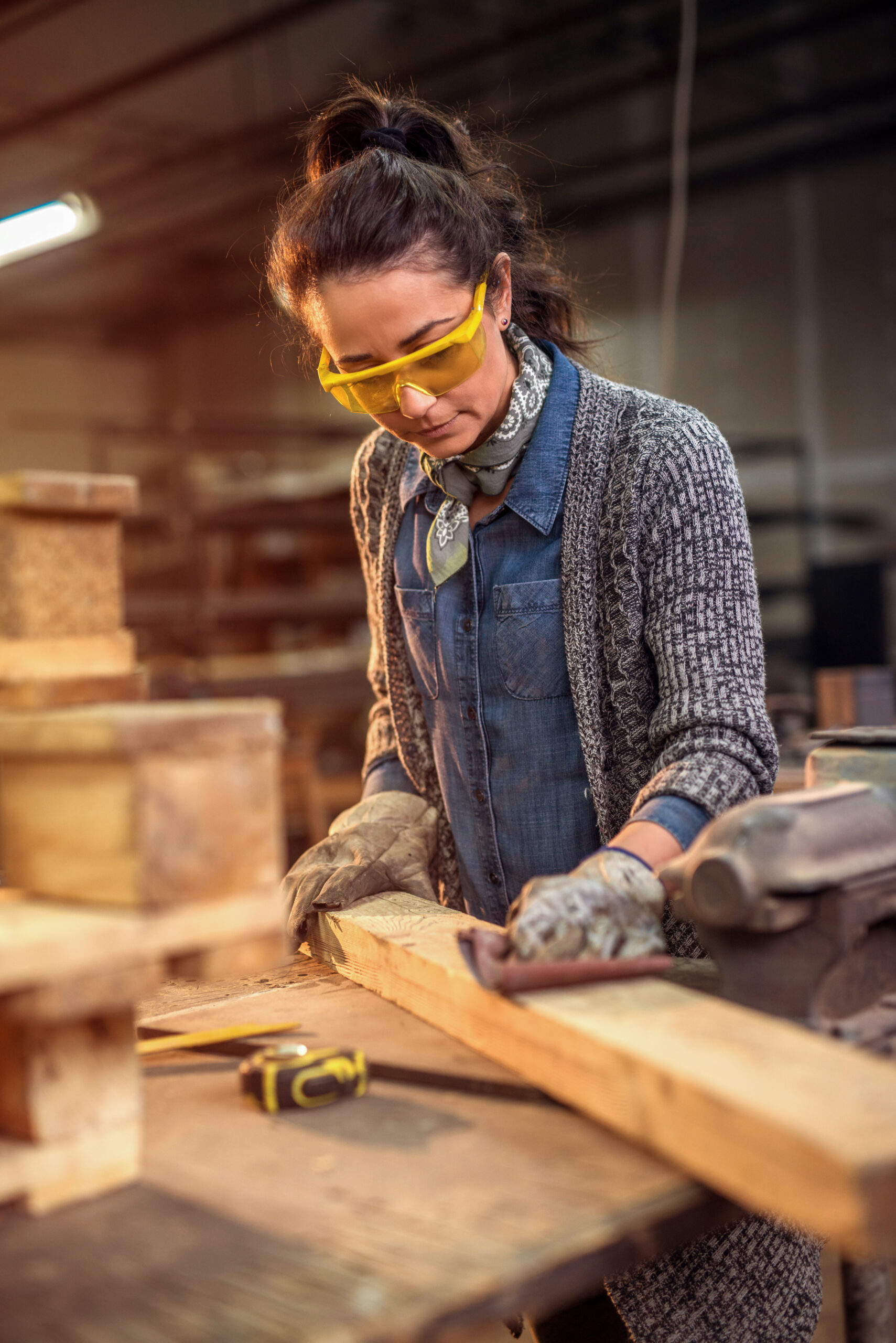 Middle aged professional female carpenter working with sandpaper in her workshop. Middle aged professional female carpenter working with sandpaper in her workshop.