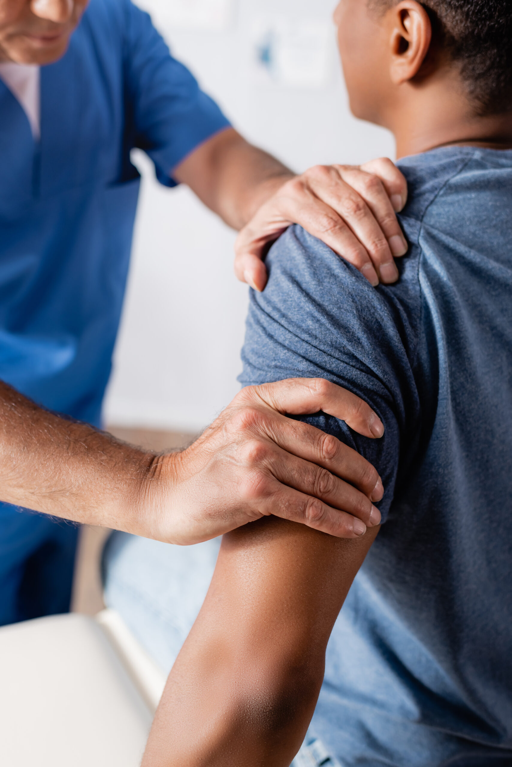 partial view of chiropractor working with injured african american man in clinic