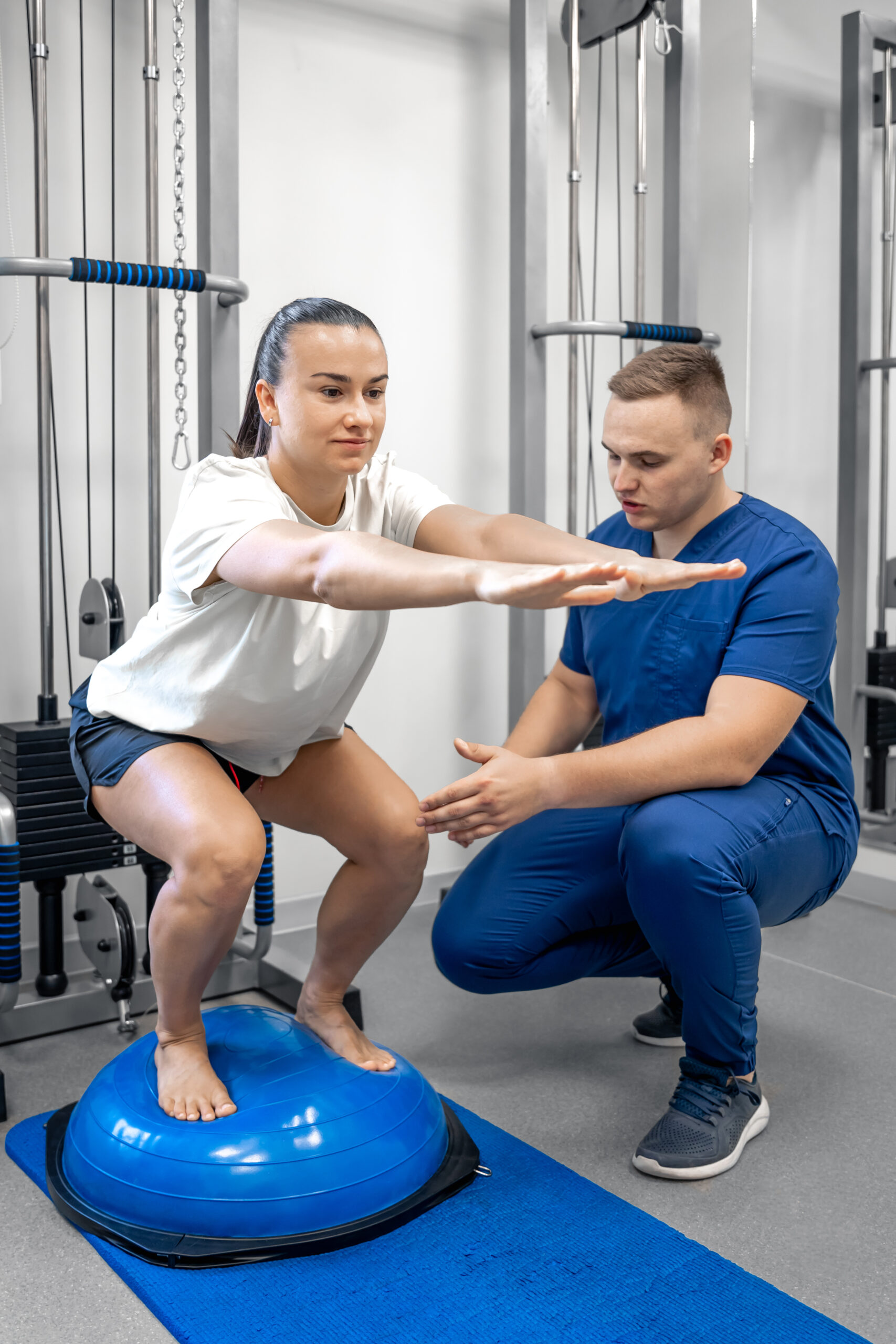 Balance exercise with bosu ball, woman and doctor in gym. Physiotherapist helping female patient with rehabilitation, balance exercise with bosu ball, woman and doctor during rehab physiotherapy in gym.